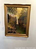 Full front view of framed oil painting showing waterfall landscape by F.W. Bater in gold wood frame.