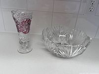 Bohemian cut crystal vase with red inlaid pattern and clear crystal bowl with fan and linear cut pattern on countertop