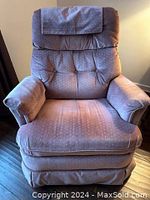 Front view of purple patterned fabric rocker recliner chair showing padded backrest with headrest flap and cushioned seat.