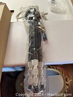 View of tripod fully collapsed, wrapped in protective plastic to preserve condition.