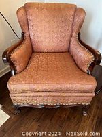 Front view of vintage armchair showing upholstery pattern and carved wood frame