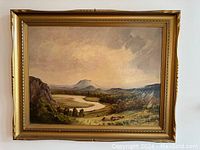 Front view of vintage landscape oil painting in gold frame showing river, valley, mountains, and cloudy sky