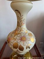 Close-up of milk glass lamp base showing detailed hand-painted white flowers with gold leaves.