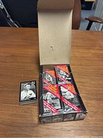 Open box showing 32 unopened baseball card packs and 4 opened card packs/cards displayed beside it