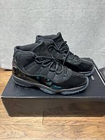 Side view of black Air Jordan 11 Retro sneakers placed on their original box.