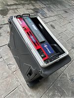 Black hard carrying case with open top showing two rack-mount electronic devices stacked inside.