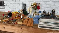 Photo showing a wide variety of items including placemats, figurines, gloves, magnets, and candles arranged on a wooden surface.