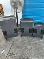 Front view of three TACH hard shell suitcases showing different sizes and black protective corner panels.