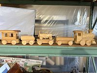 Full side view of the four wooden train cars connected: locomotive, two flat cars, and caboose, showing size and overall design.