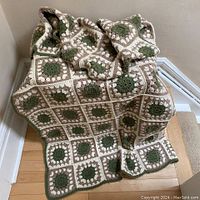 Full view of hand crocheted blanket draped over a chair, showing overall pattern and size