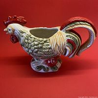 Side view of ceramic creamer shaped as a rooster showing profile and base details.