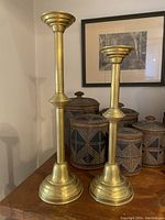 Full view of both brass candlesticks on wooden surface