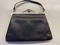 Full view of front of black textured leather evening bag with silver-tone metal frame and leather handle