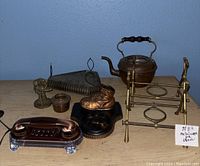Overall view of collection including copper teapot, boot door knocker, brass holder, multi-wheel stand