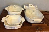 CorningWare blue and white dishes with glass lids and metal rack on wooden surface