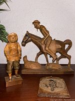 Two hand-carved wooden festival figurines and one wooden bird coaster displayed together, showing details and scale.