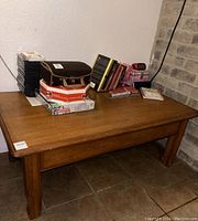 Full view of the mid-century modern solid wood coffee table with a pullout drawer, showing the top surface cluttered with various items (not included in sale).