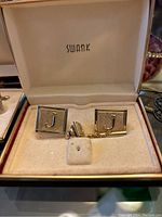 Close-up of a set of Swank cuff links monogrammed 'J' in original box.