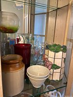 Wide view showing all items including stained glass rose holder, pottery vases, glass jars, red and clear vases, and white pottery jar
