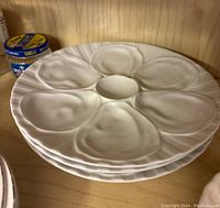 Three white oyster plates with shell-shaped sections stacked