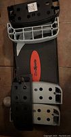 Top-down photo of black rectangular Zen Sports exercise platform with red logo visible. Four black and gray plastic attachment pieces placed on top with holes for foot or hand placement.