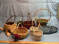 Photo showing assortment of nine decorative baskets including stuffed monkey basket and various woven wicker baskets in different colors and sizes.