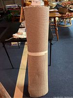 Rolled new beige Berber carpet remnant standing upright. Clearly shows approximate length (94") and width (48").