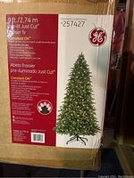 Box showing 9 ft artificial tree with GE branding, Just Cut Fraiser Fir pre-lit with 3252 clear lights.