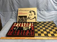 Complete chess set including pieces displayed in original box with labeled cover and chessboard laid out to the side.