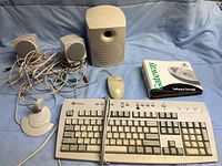 All included Gateway computer peripherals laid on blue cloth: keyboard, mouse, three speakers, microphone on stand, and software box.