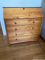 Pine dresser closed with drop-front writing surface closed; wood grain and round knobs visible