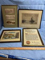 Set of four framed decorative wall art pieces arranged on floor, including maritime and cityscape themes and document-style art.