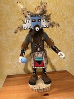 Full view of the W. Hoskie artist signed Hopi Kachina doll standing on wooden base with feathers on the headpiece and detailed costume.