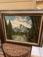 Full view of framed landscape oil painting showing Half Dome at Yosemite with river and trees.