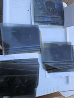 Top-down view of multiple glass photo negatives stacked in groups showing varying transparency and image clarity on glass plates.