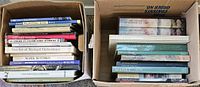 View of two open cardboard boxes containing art books with various titles visible on top and edges.