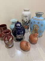Photo showing all 8 pieces: 5 vases, 1 lidded jar, and 2 terracotta birds, various colors and designs.