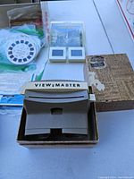 Photo showing 1950s Sawyer Bakelite View-Master viewer in original box, along with travel reels and cardboard packets.