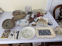 Overview of assorted pottery and ceramic items laid out on table showing variety of shapes, colors, and designs