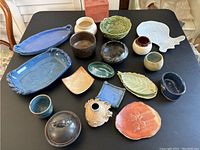 All pottery pieces arranged on a table, showing variety of shapes, sizes, and colors.