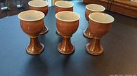 Front view of all six ceramic goblets, showing consistent shape and color, arranged on a black surface.