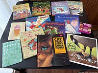 Eleven colorful children's books showing titles and cover illustrations arranged on a black surface.