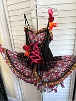 Front view of colorful Day of the Dead themed dress with sugar skull print, lace-up pink front detail, flower decorations and ruffled skirt.