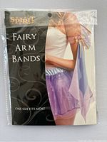 Front of sealed package showing product name with image of the arm bands worn on a model arm, showcasing flowing pastel fabric and decoration.