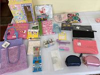 Full view of lot showing various girls' sundries including jewelry, bags, books and stationery items spread out on a table.
