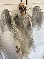 Front close-up of the hanging skeleton angel of death decoration showing skull head, tattered fabric robe and wings, and skeletal hands.