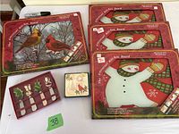 Four kitchen boards in original packaging with Christmas designs (three snowmen, one cardinal birds) plus new Christmas-themed spreaders and coasters.