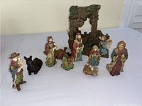 Full view of all nativity scene figures including Mary, Joseph, baby Jesus, three wise men, shepherd, animals, and the manger stable backdrop on a white surface.