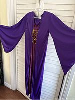 Full view of the purple gown hanging on hanger showing large wide sleeves and full length