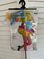 Packaged rainbow tutu in plastic with model image on front showing the tutu worn with pink fishnet stockings.